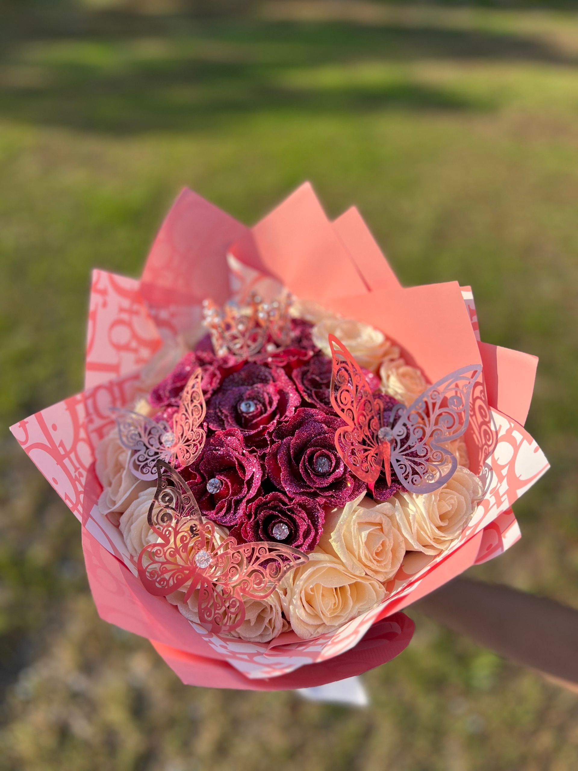 A person is holding a bouquet of flowers wrapped in pink paper.