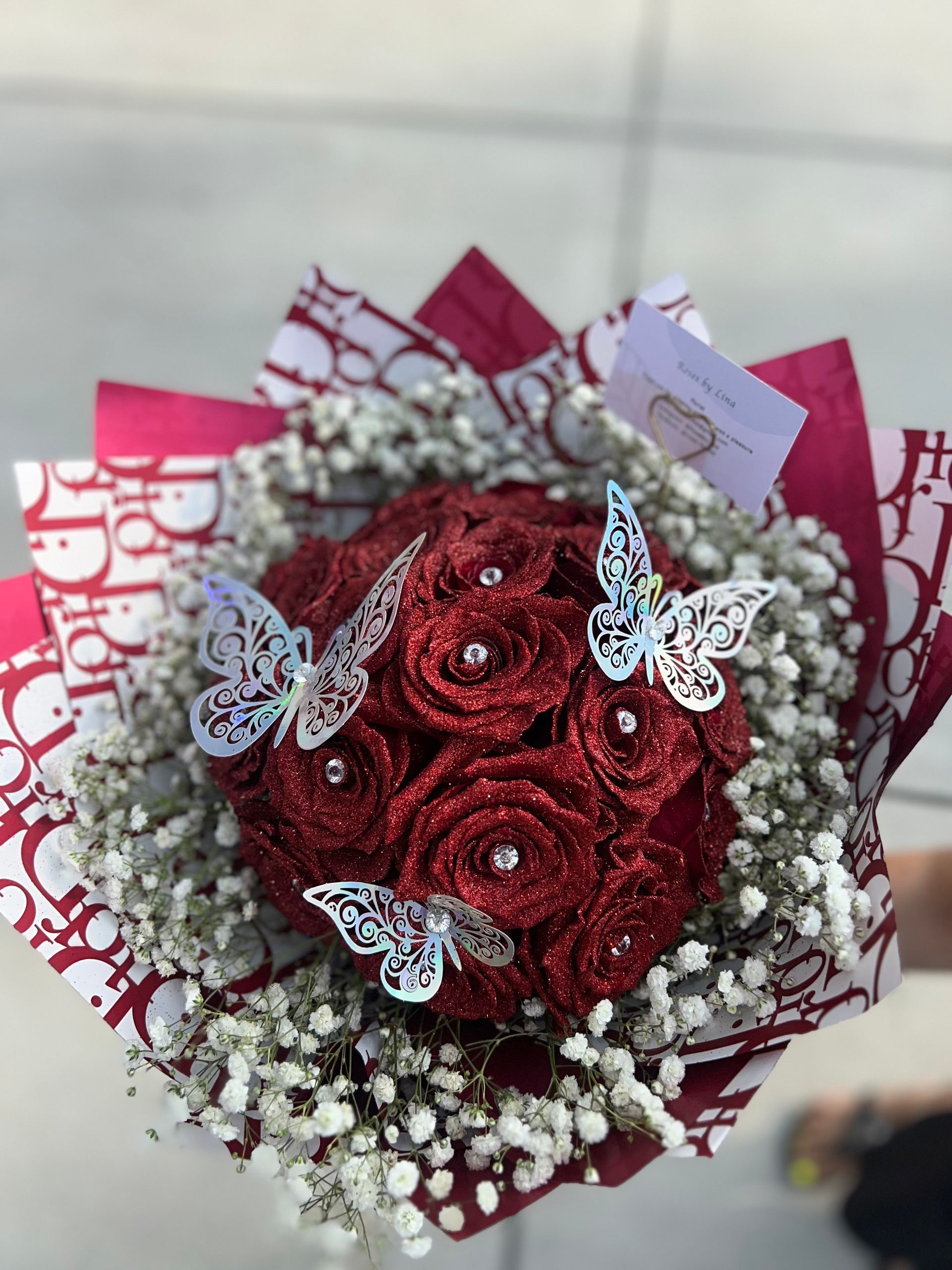 A bouquet of red roses with white baby 's breath and butterflies