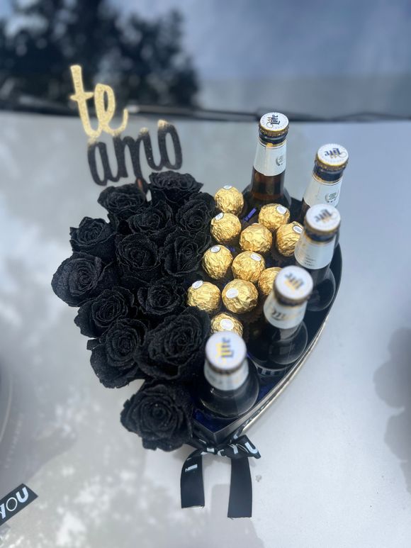 A heart shaped bouquet of black roses and beer bottles
