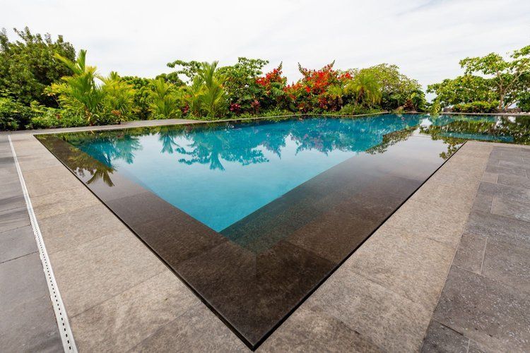 A woman is swimming in a swimming pool surrounded by palm trees.