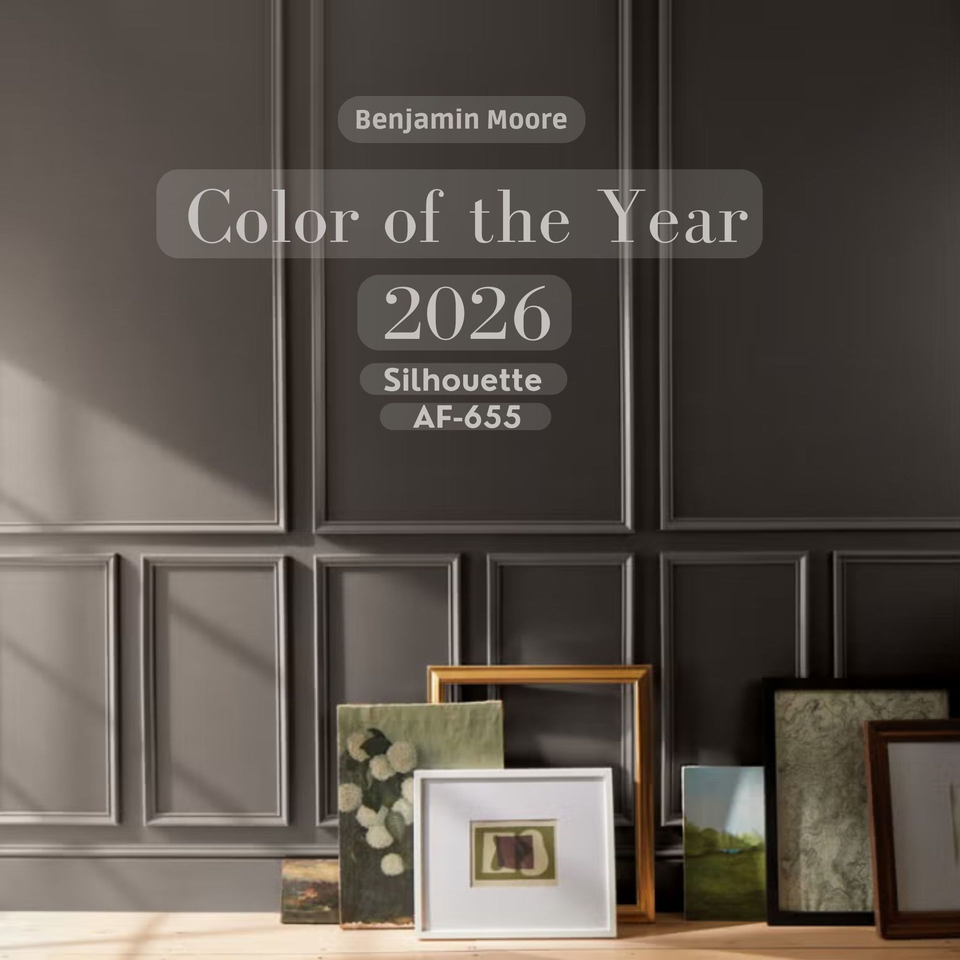 Benjamin Moore's Color of the Year 2026: Silhouette (AF-655). A dark gray wall with picture frames on a wooden floor.