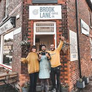 Three staff members standing in the doorway of Brook Lane Coffee Co