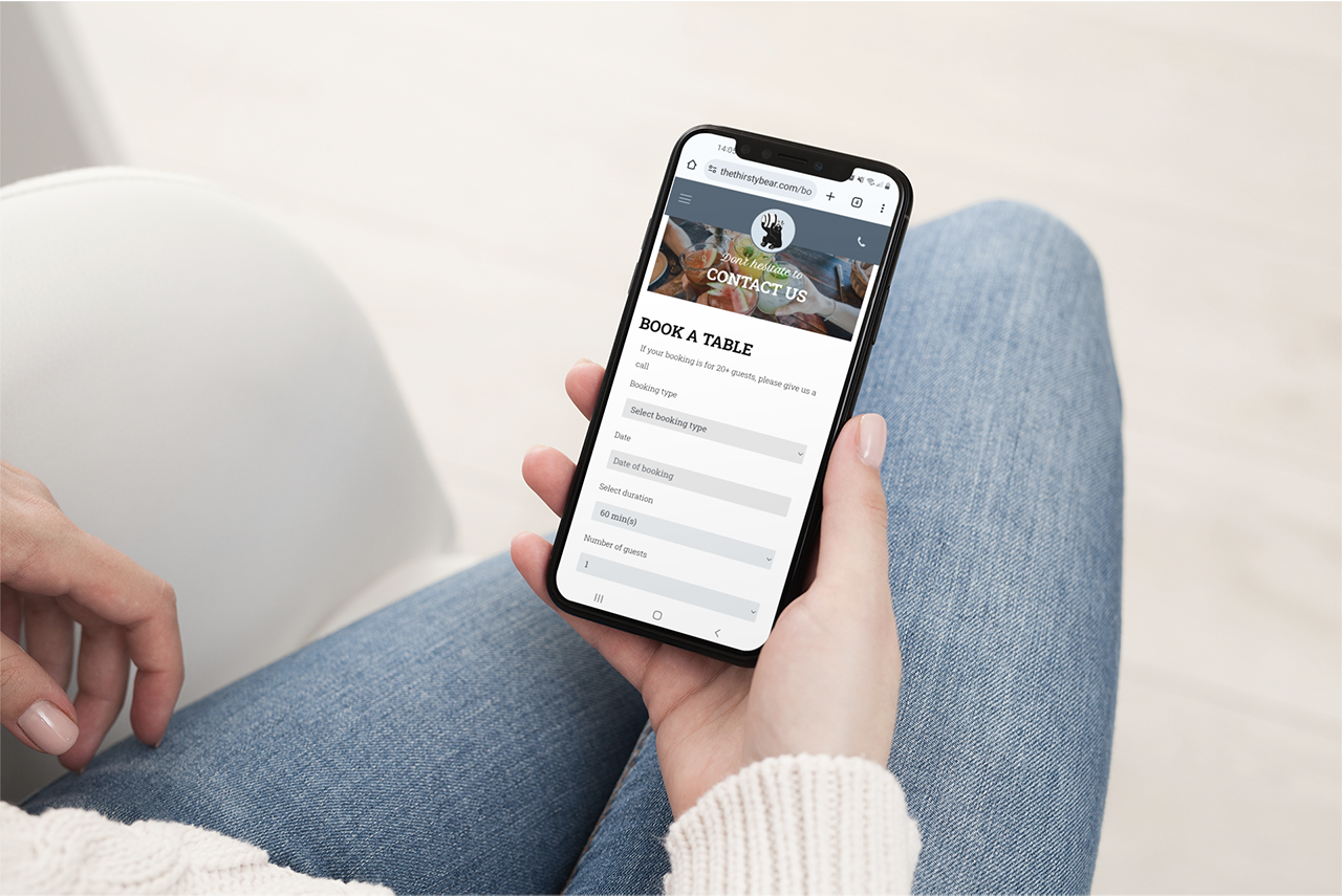 a woman's hand holding a phone, which shows the online booking form of a restaurant