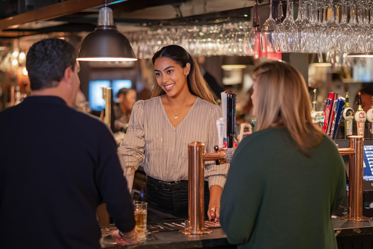 Hands holding a tablet displaying a restaurant point-of-sale interface with various menu buttons