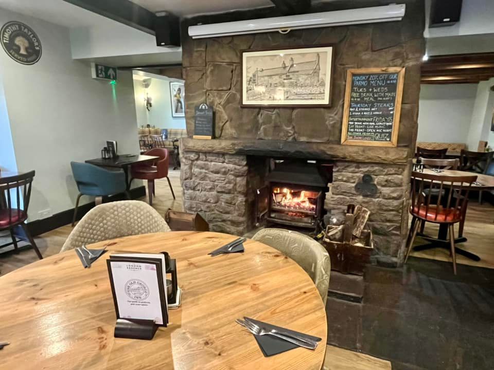 The interior of a country pub with wooden tables and a fireplace with original masonry