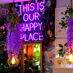 A decorative pink neon sign in a restaurant that says 'This is our happy place'
