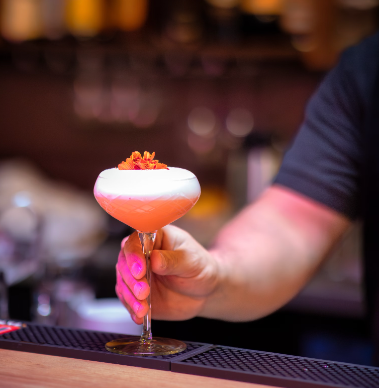 A bartender placing a cocktail on a bar