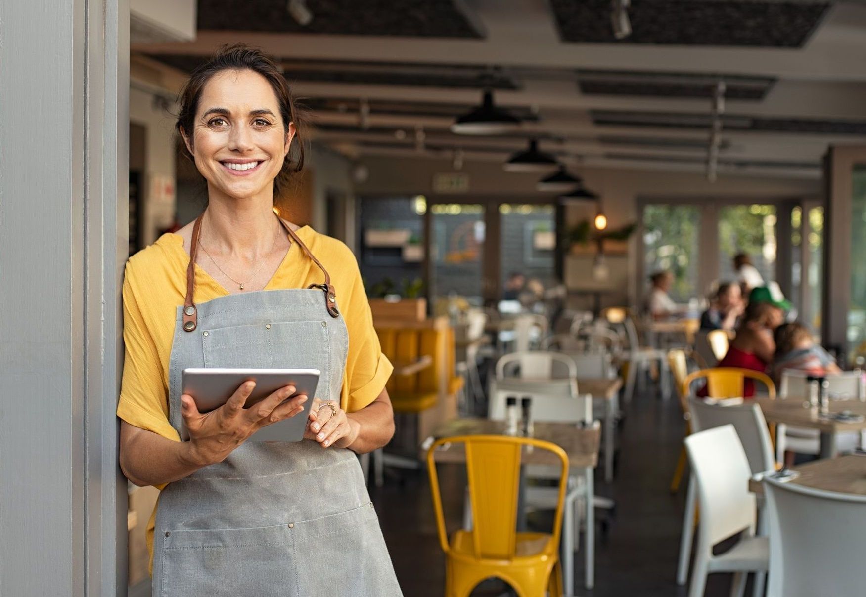Smiling lady standing in front of a bar with iPad EPOS