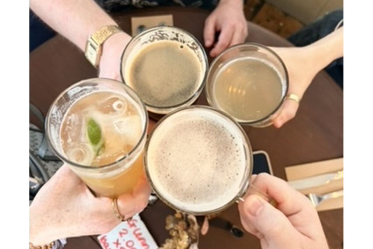 Four people toasting drinks: beer and cocktails