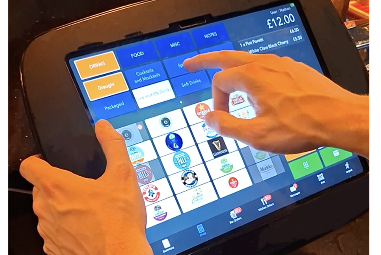 Hands using a touchscreen POS register with colorful menu buttons on a tablet screen.