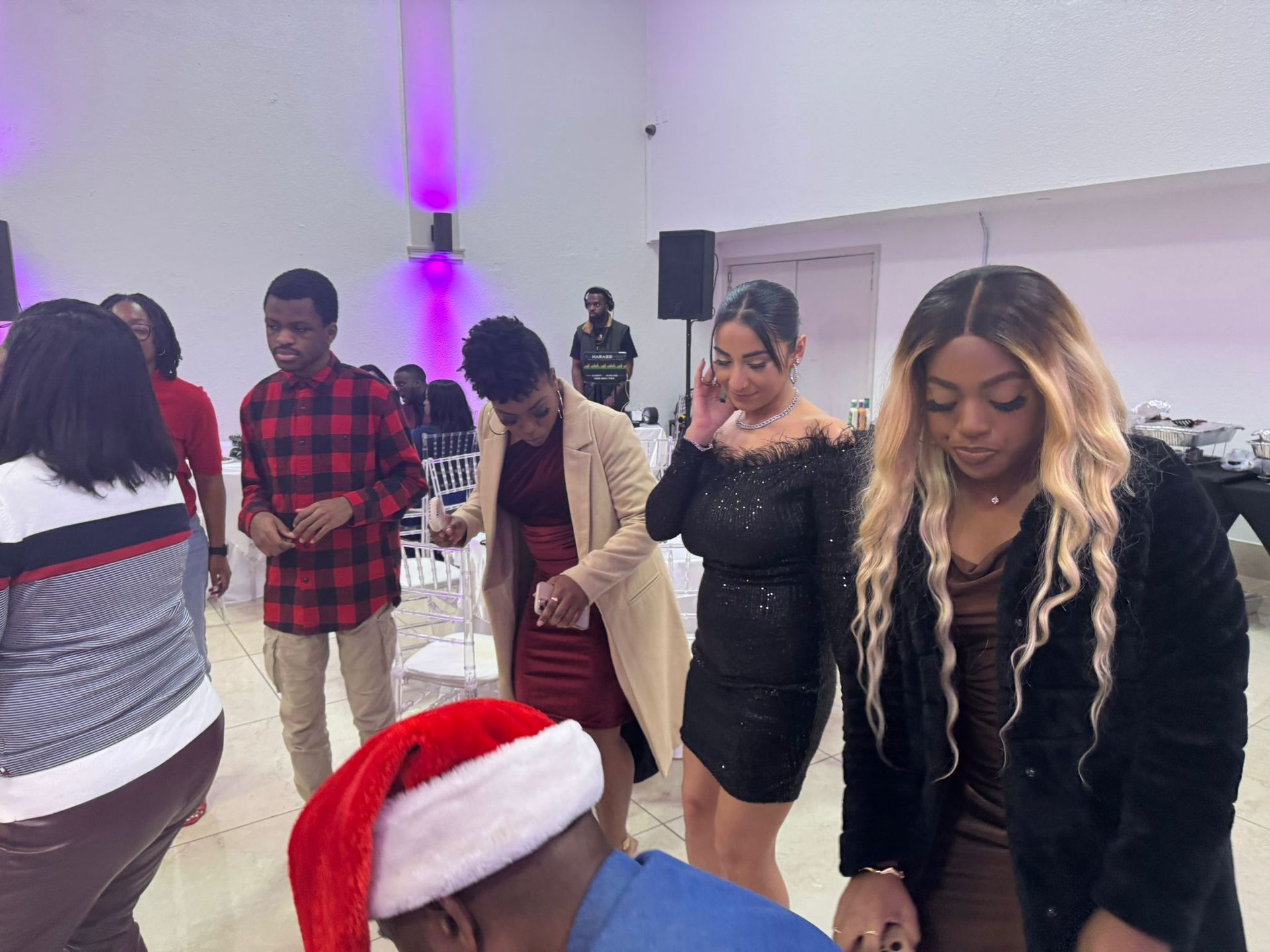 A group of people are standing around a man wearing a santa hat.