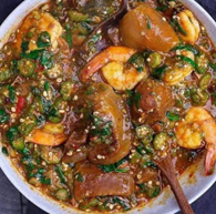 A bowl of okra and shrimp stew with a wooden spoon in it.