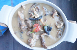 A bowl of soup with meat and mushrooms in it
