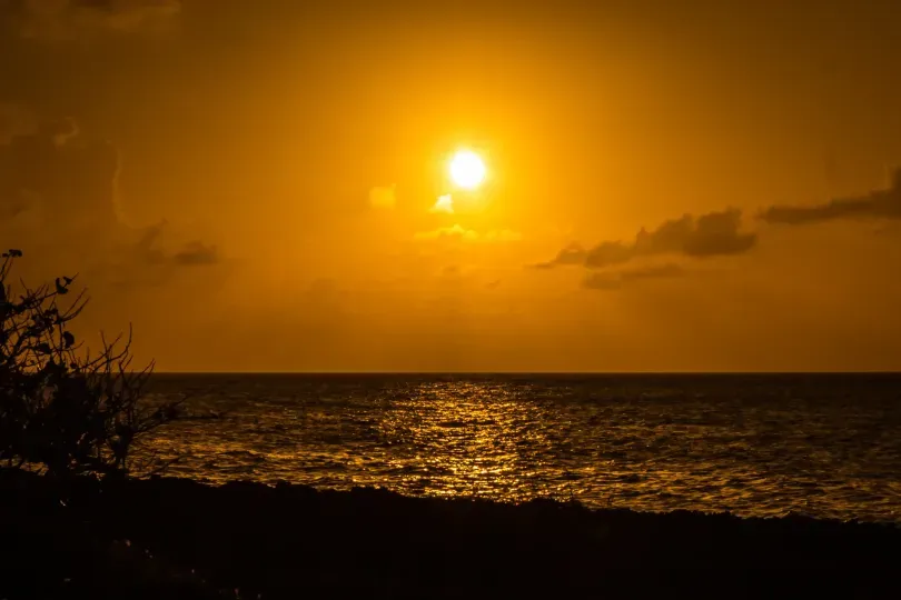 Atardecer en San Andrés con vista al mar Caribe, cielo anaranjado y sol reflejado en el océano.