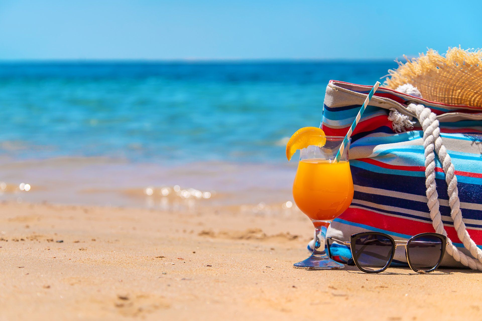 Maleta de playa y bebida frente al mar en San Andrés, ambiente ideal para vacaciones de descanso.