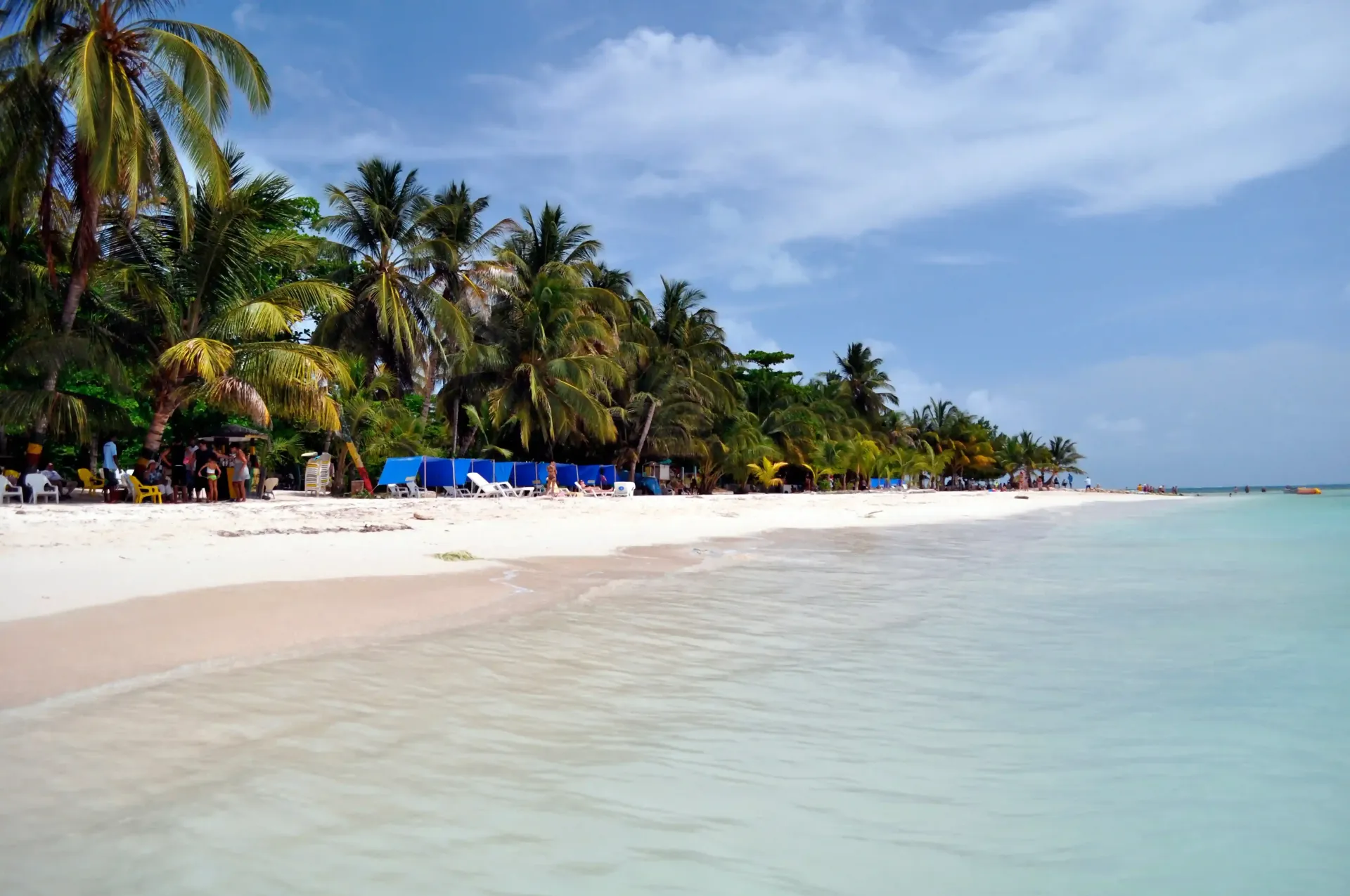 Playa de San Andrés tranquila, arena blanca, palmeras verdes, destino turístico.