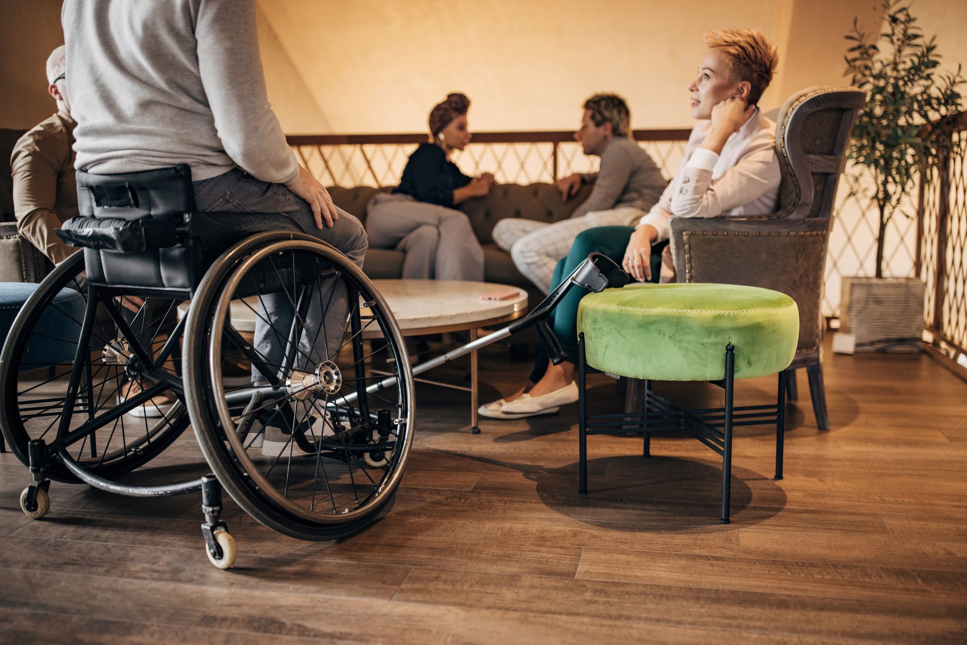 Persone sedute in un accogliente soggiorno, con una persona in sedia a rotelle in primo piano.
