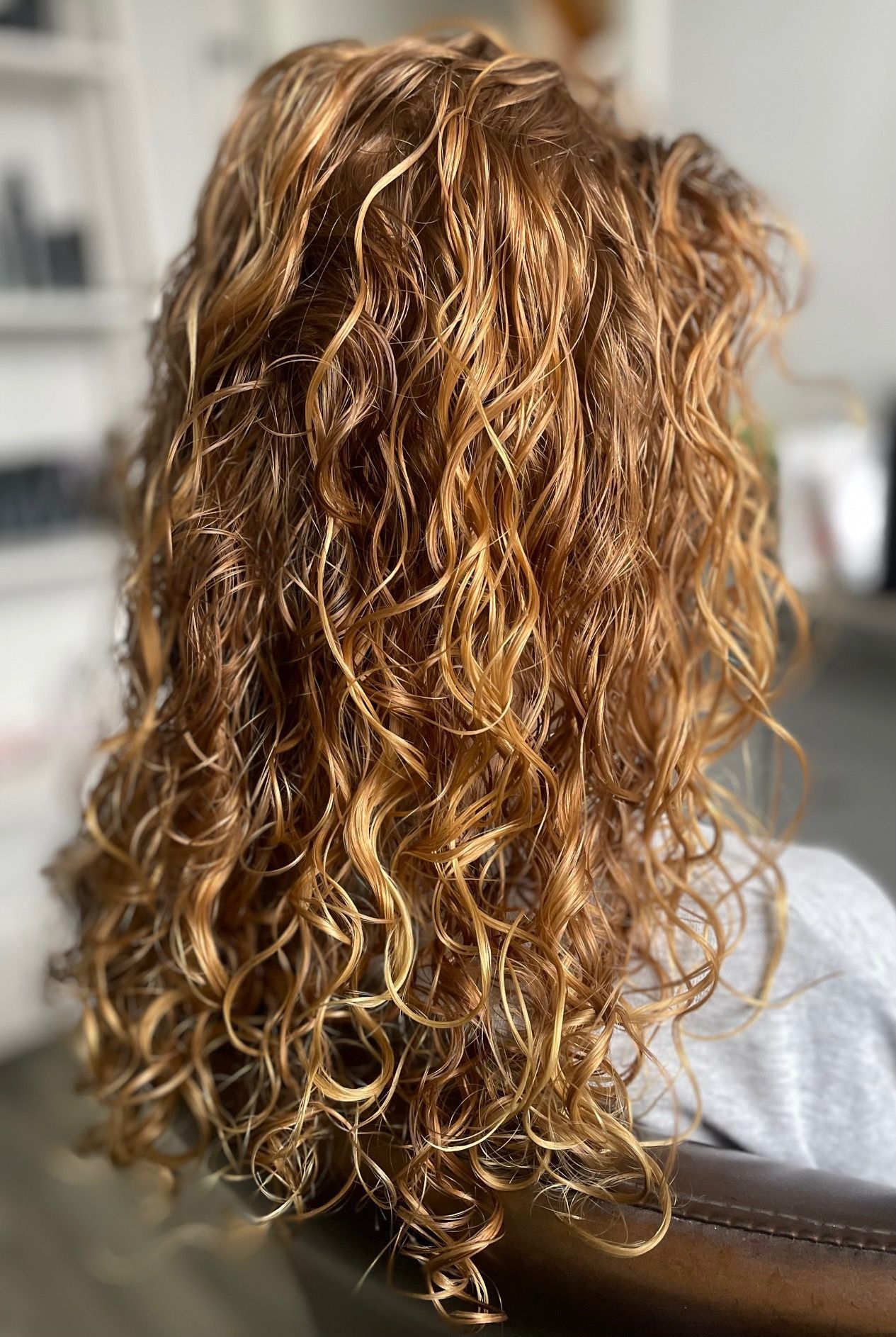 Lang goudbruin haar met krullen, van achteren gezien.