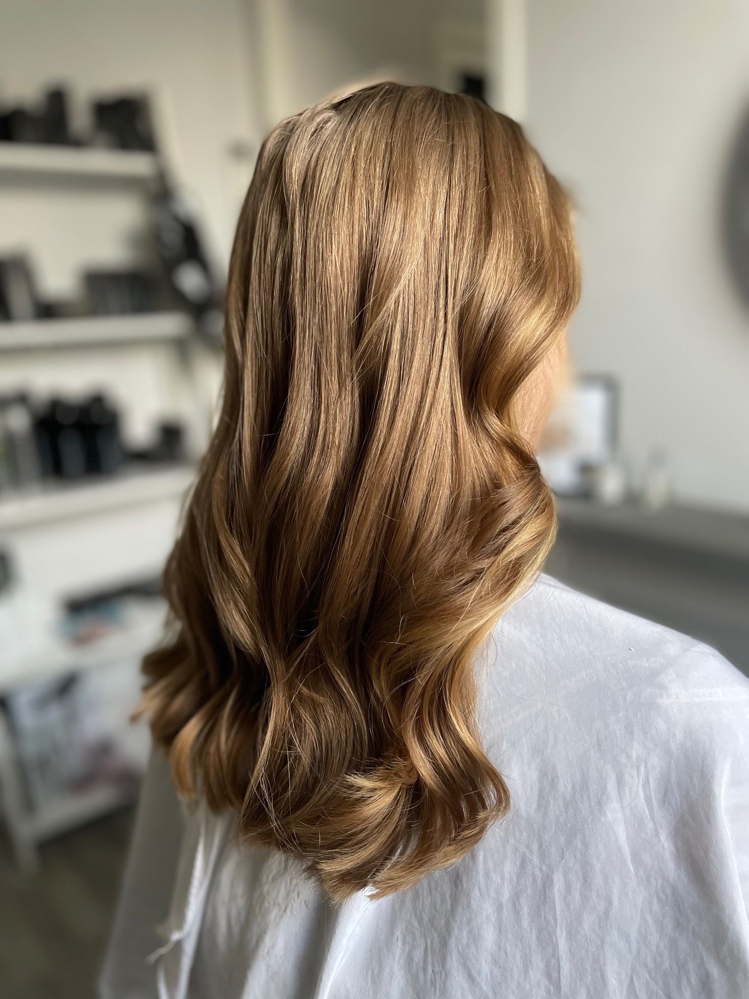 Lang goudbruin haar met golven, van het gezicht af gestyled.