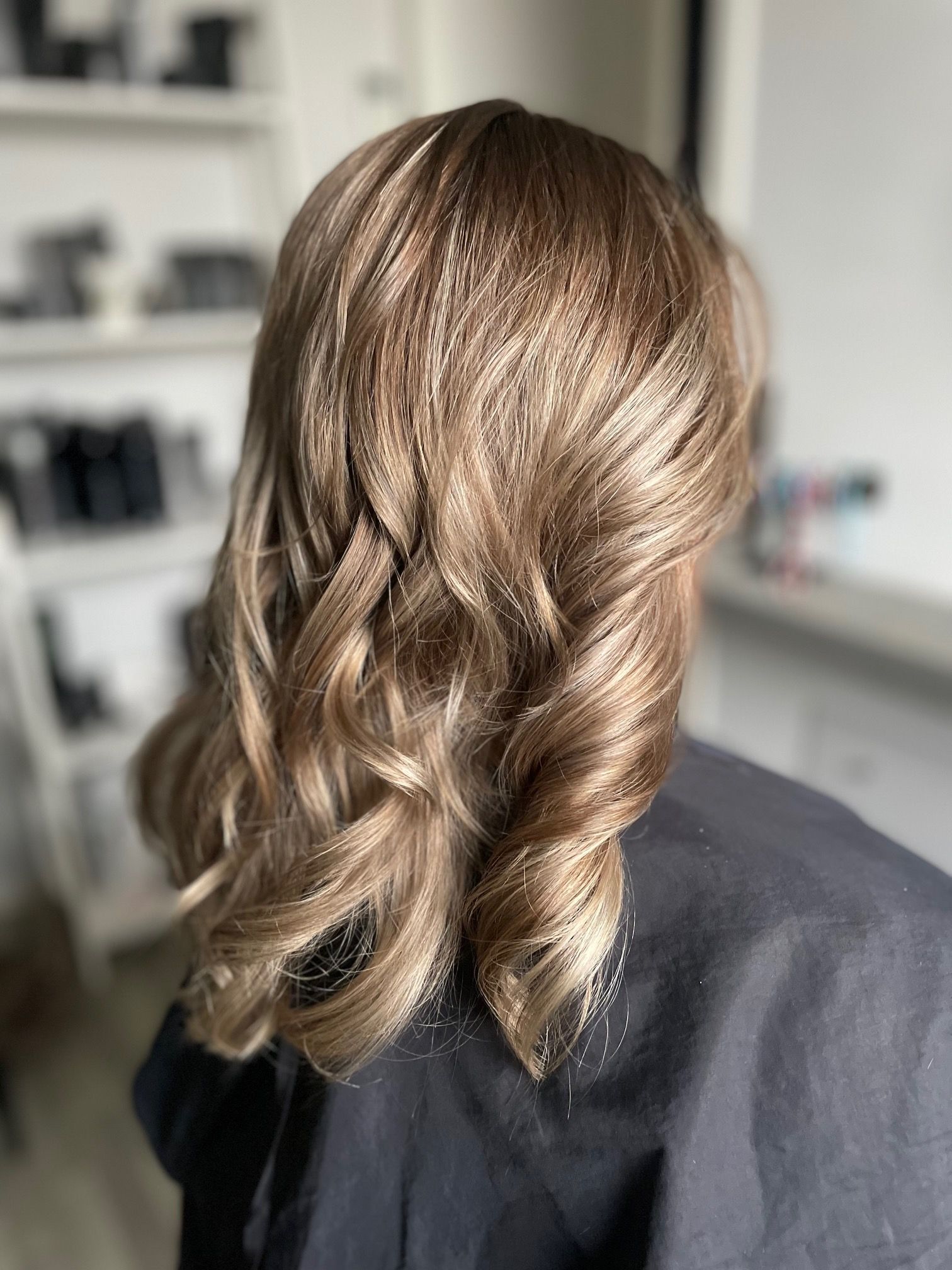 Half opgestoken kapsel met losse golven in blond haar.