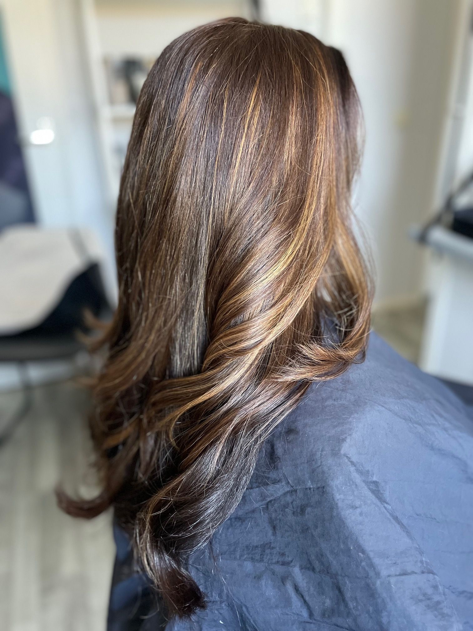 Bruin haar met subtiele highlights, gestyled in losse krullen.