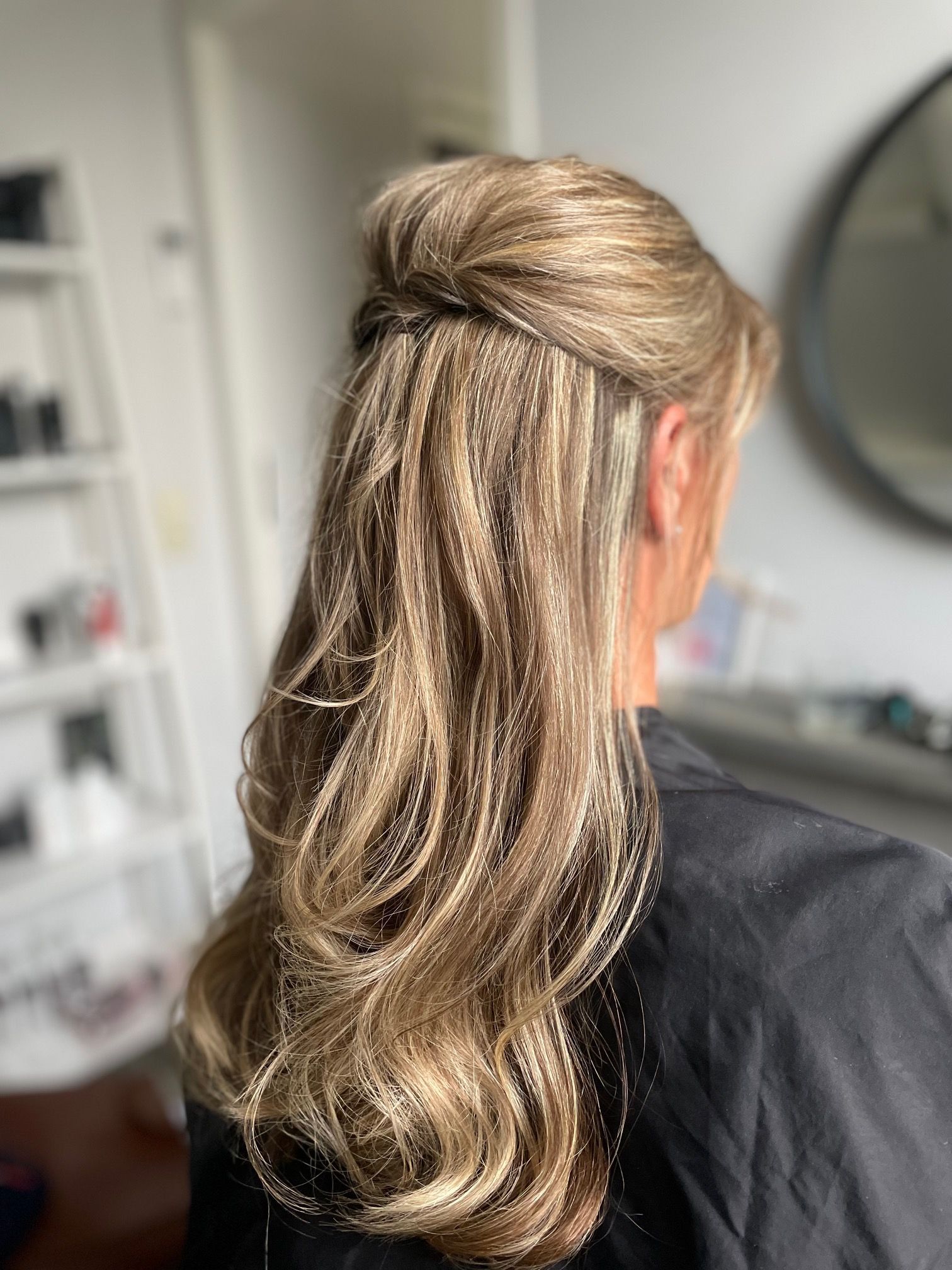 Blond haar opgestoken in een half opgestoken kapsel met losse golven.