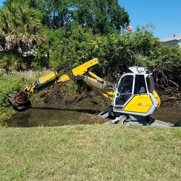 A yellow and white excavator is cleaning a body of water.