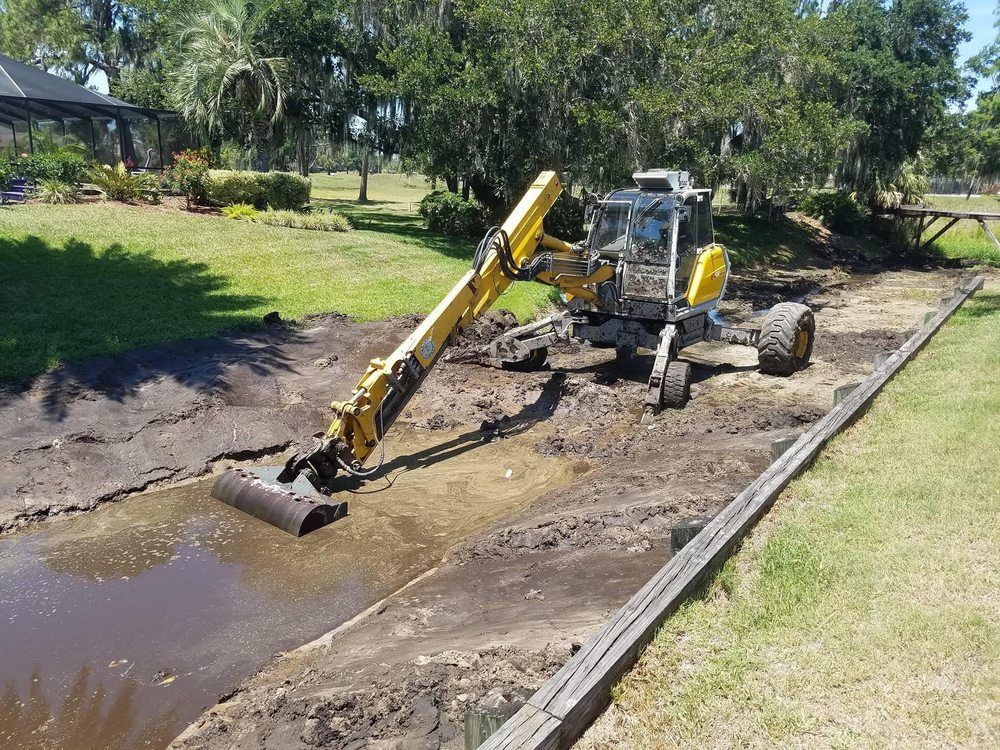 A yellow excavator is sitting in the middle of a field.