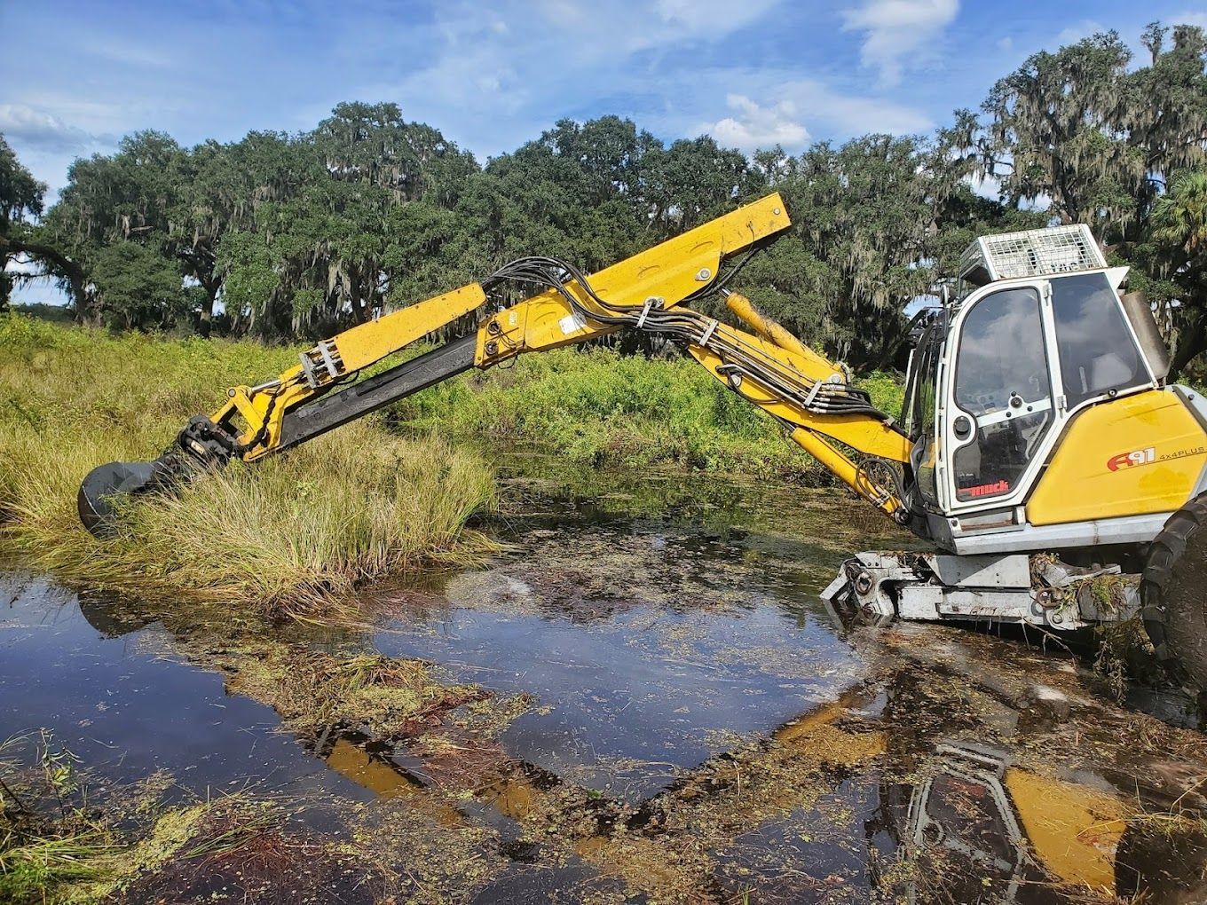 A yellow excavator is digging in a muddy field.