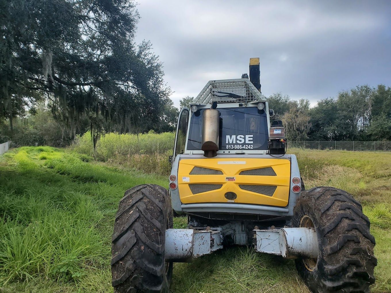 A tractor is parked in a grassy field with trees in the background.
