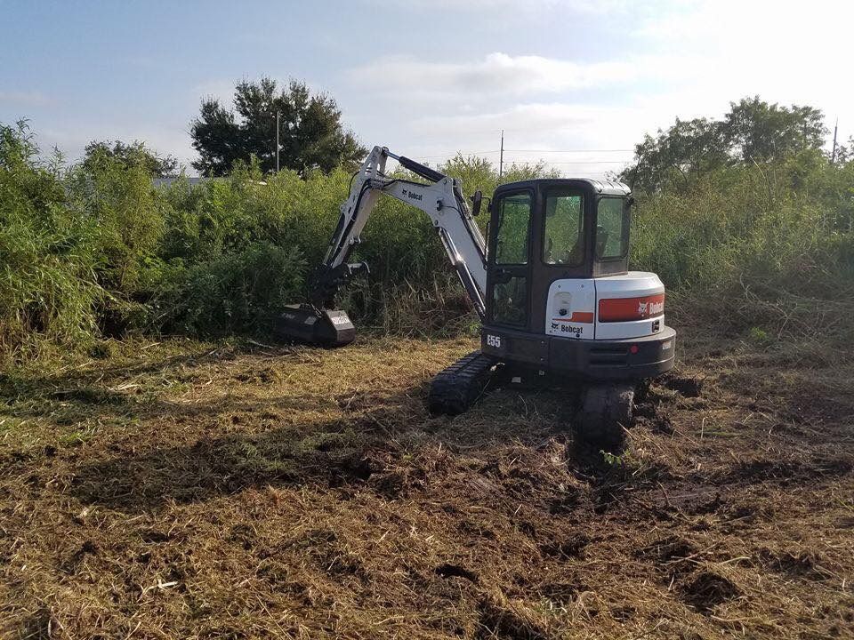 A small excavator is sitting in the middle of a field.