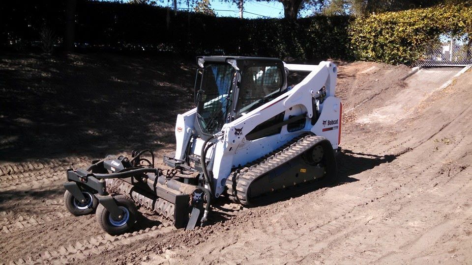 A bobcat tractor is driving down a dirt road