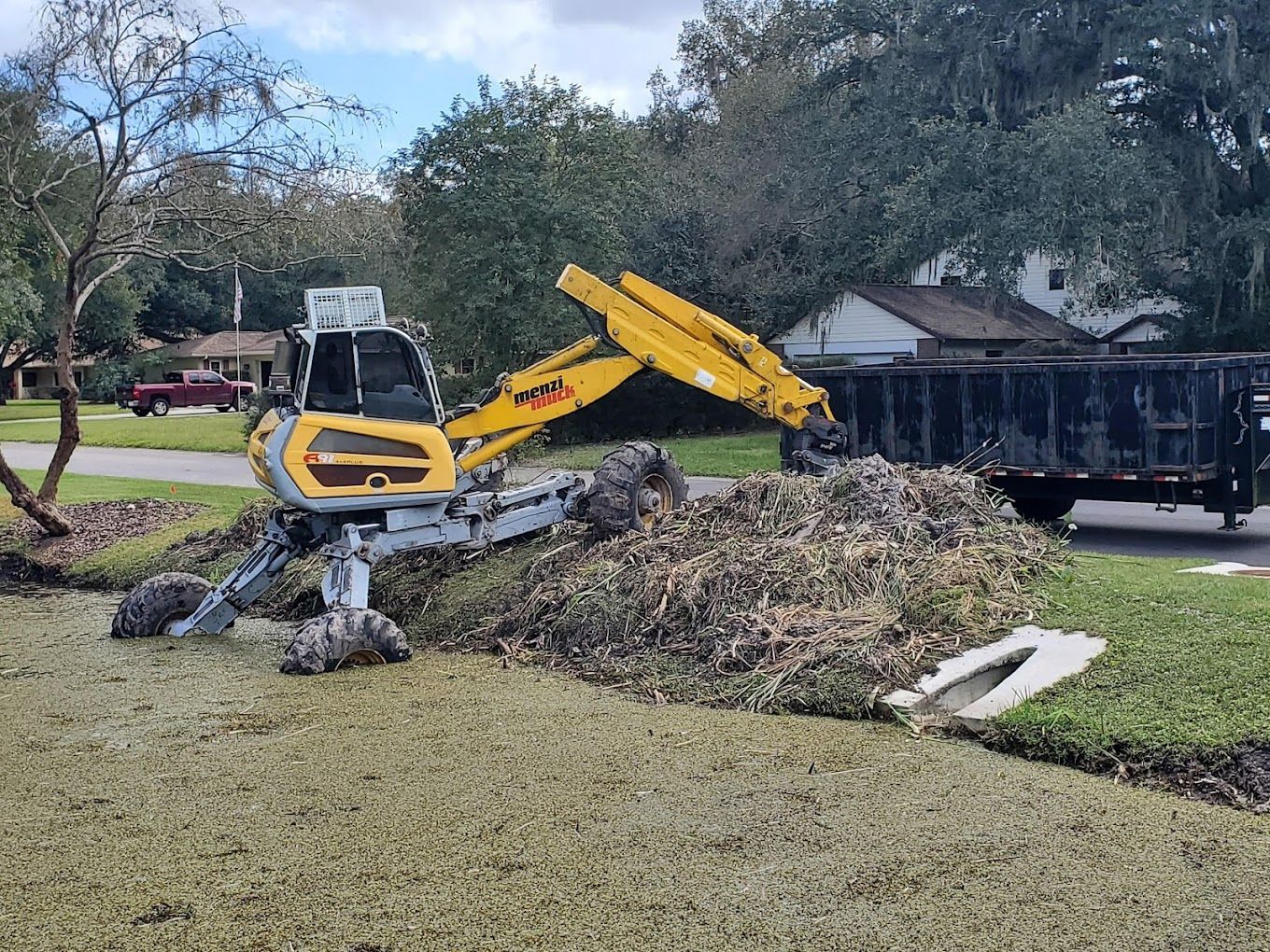 A yellow excavator is moving a pile of dirt in a yard.