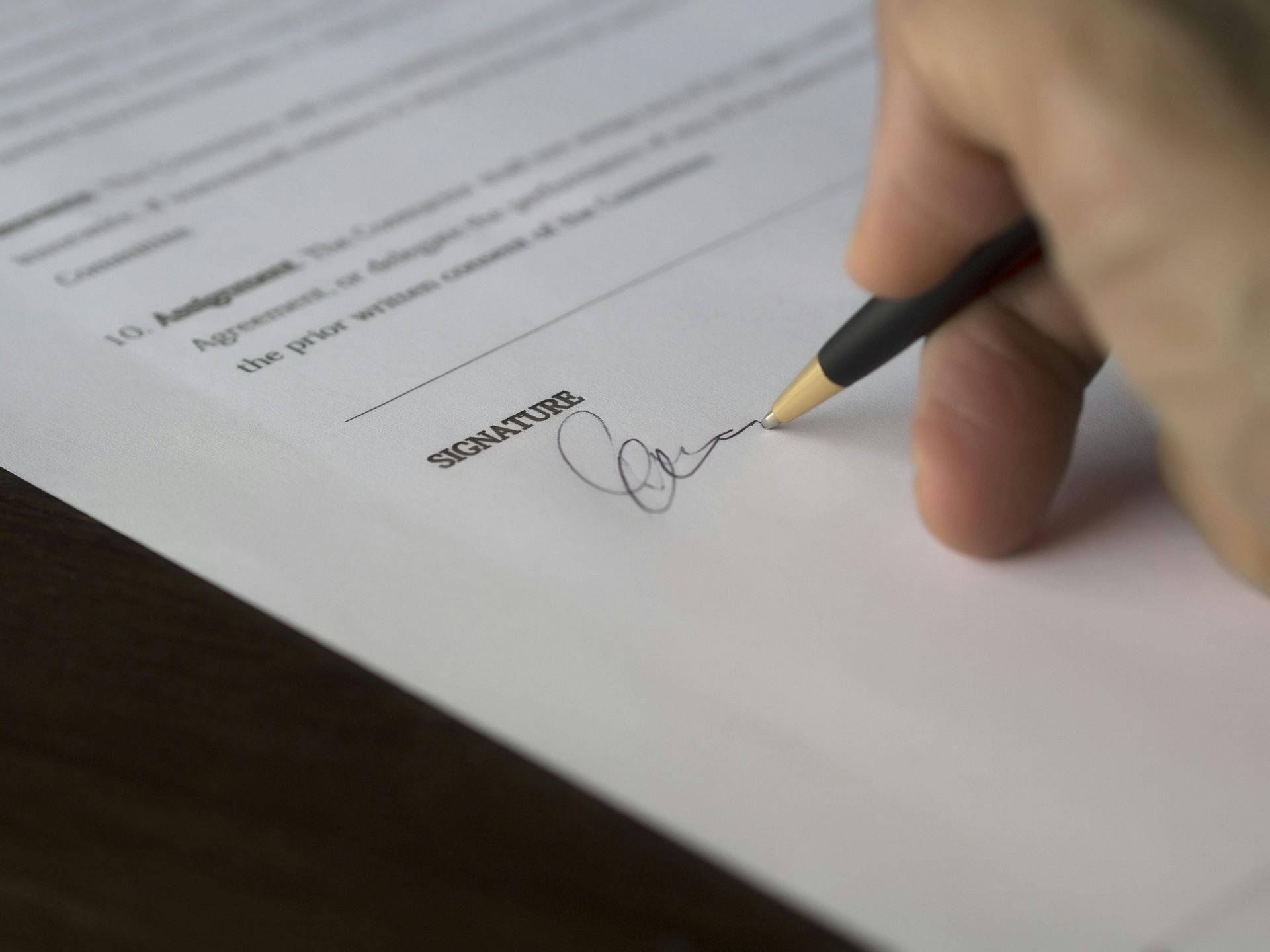 Hand signing a document with a pen close-up on white paper