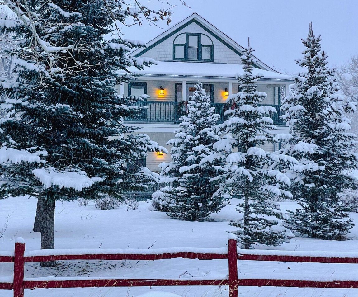 A snowy house with a red fence in front of it