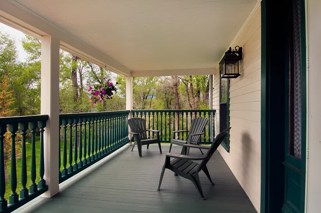 A porch with chairs and a lantern on it