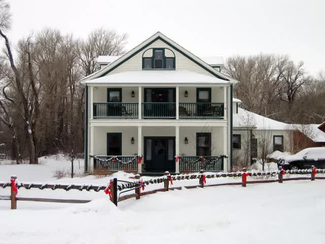A snowy house with a fence in front of it