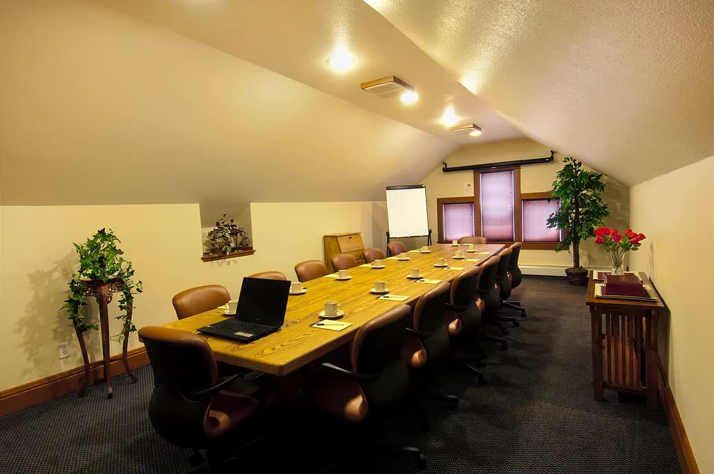 A conference room with a long table and chairs and a laptop on the table.