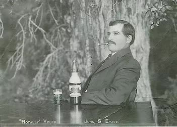 A man is sitting at a table with a bottle of beer and a glass of beer.