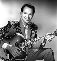 A black and white photo of a man in a suit holding a guitar.