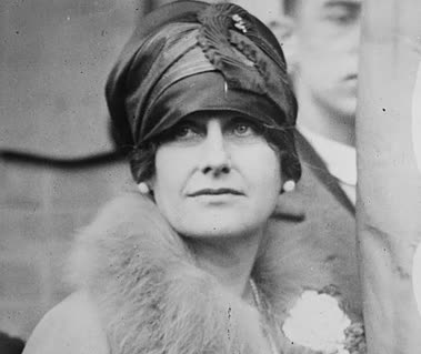 A black and white photo of a woman wearing a hat and fur coat.