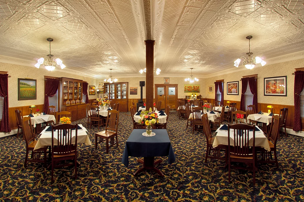 A large dining room with tables and chairs and a blue table cloth