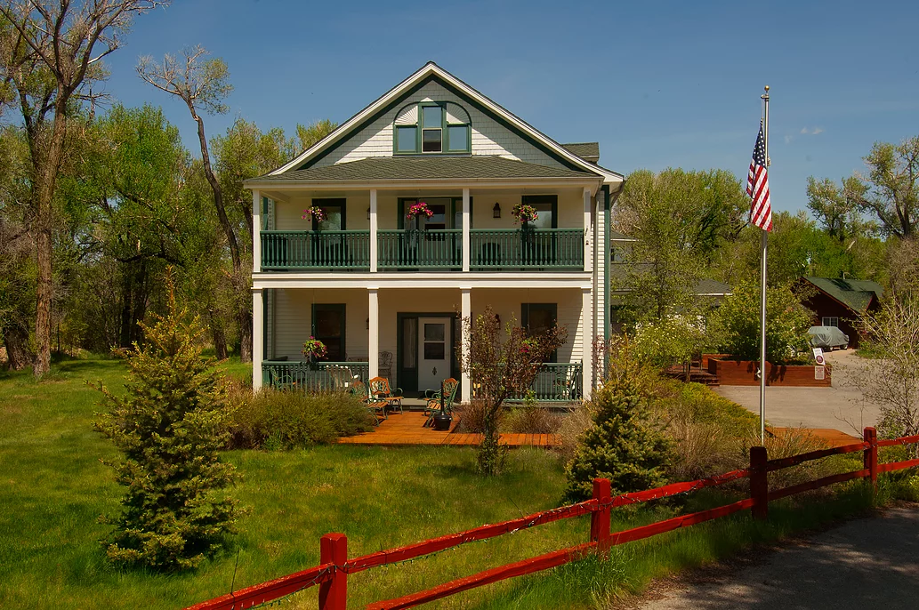 A large white house with a red fence in front of it.