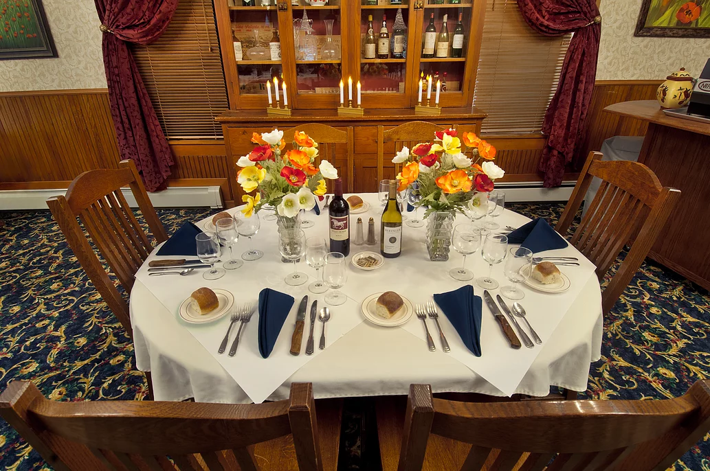 A dining room table with a white table cloth and flowers on it