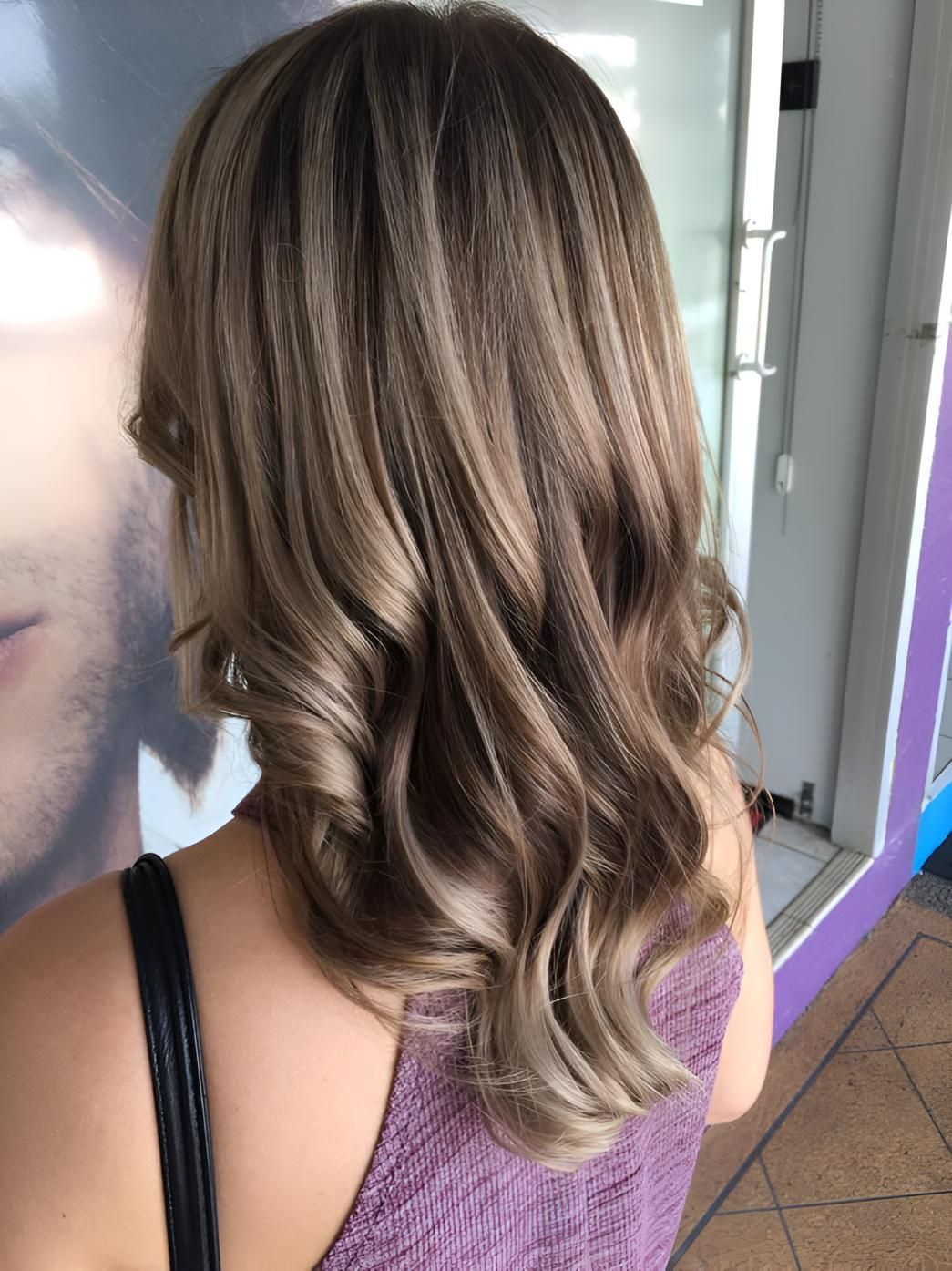 A Woman With Long Hair Is Standing In Front Of A Mirror — Klic's Hair Design In Earlville, QLD