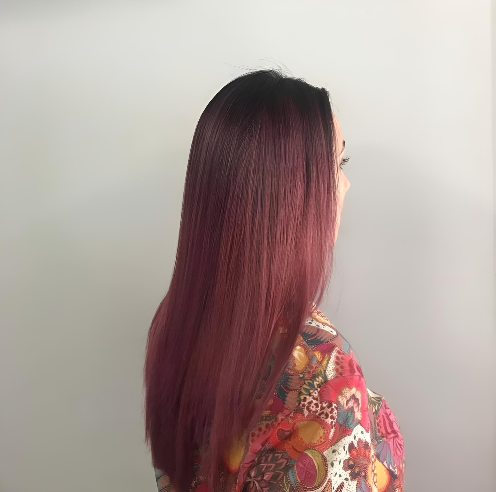 A Woman With Long Red Hair Is Standing In Front Of A White Wall — Klic's Hair Design In Earlville, QLD