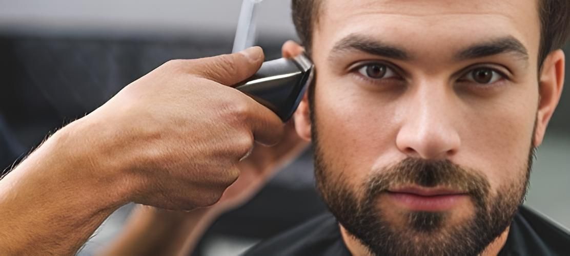 A Man With A Beard Is Getting His Hair Cut By A Barber — Klic's Hair Design In Earlville, QLD