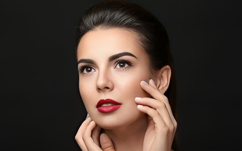 A Woman With Red Lipstick Is Touching Her Face — Klic's Hair Design In Earlville, QLD