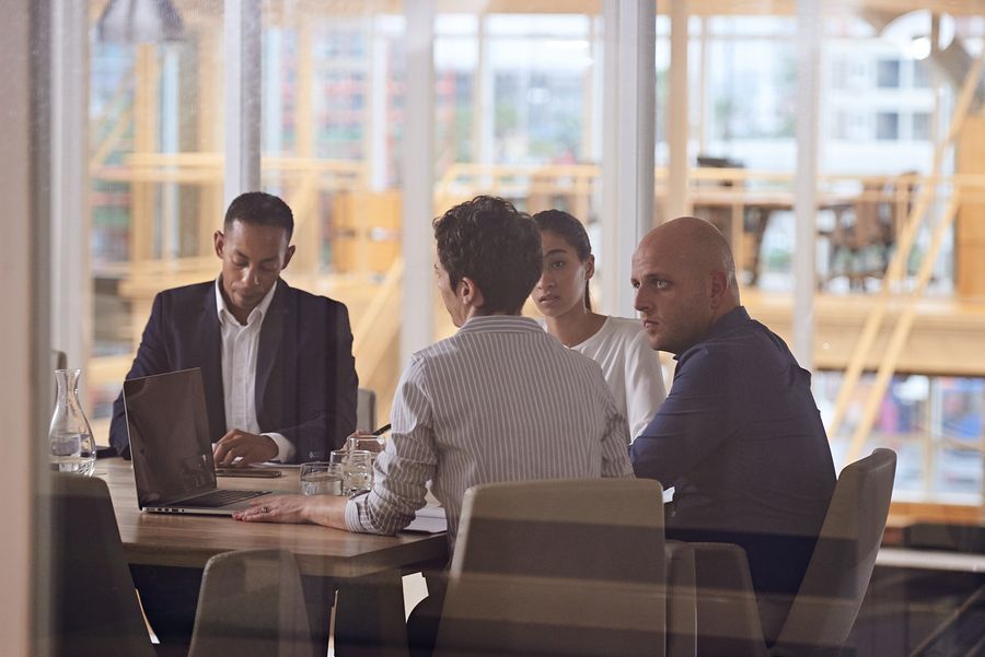 A group of people are sitting around a table with a laptop.
