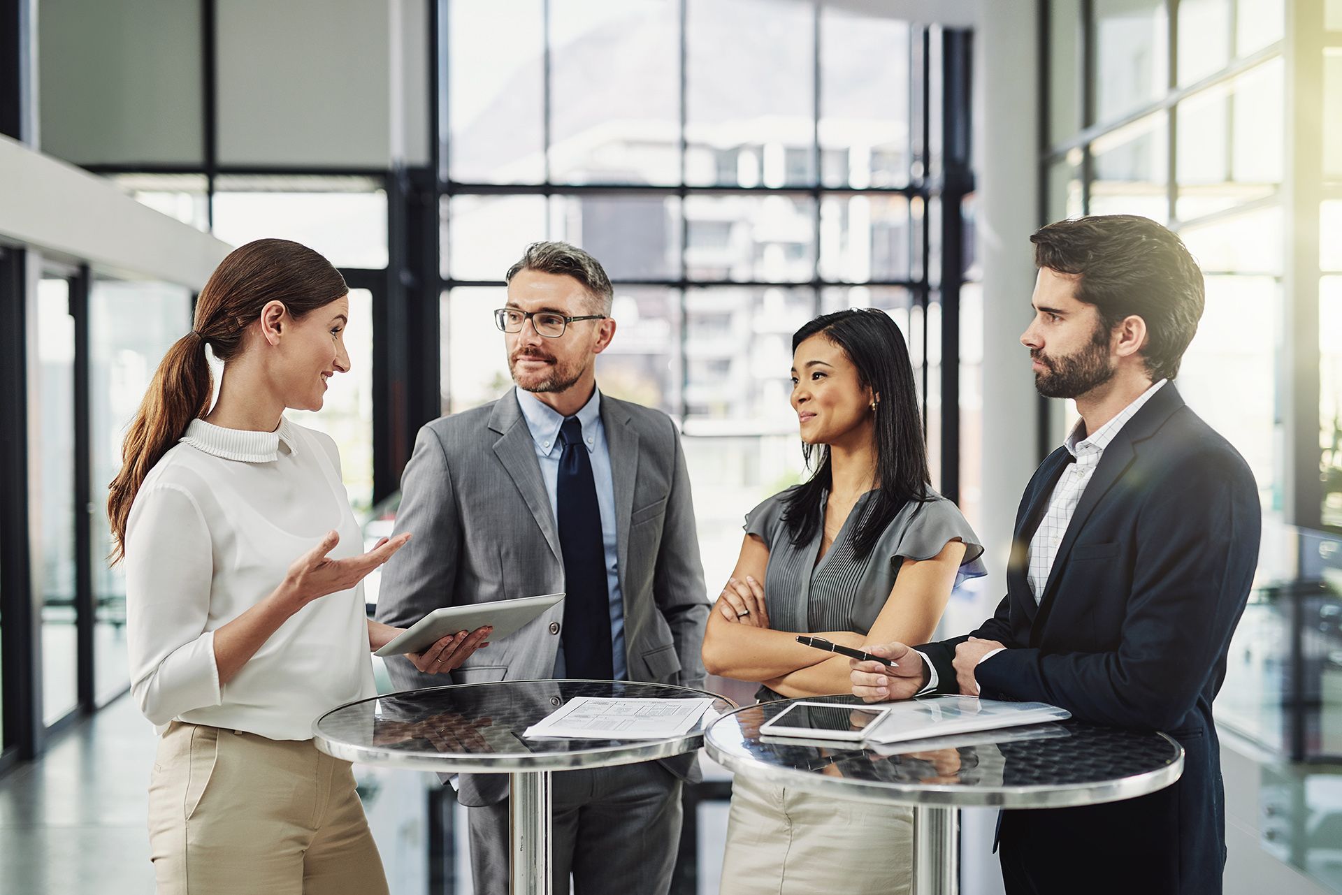A group of business people are standing around a table having a meeting.